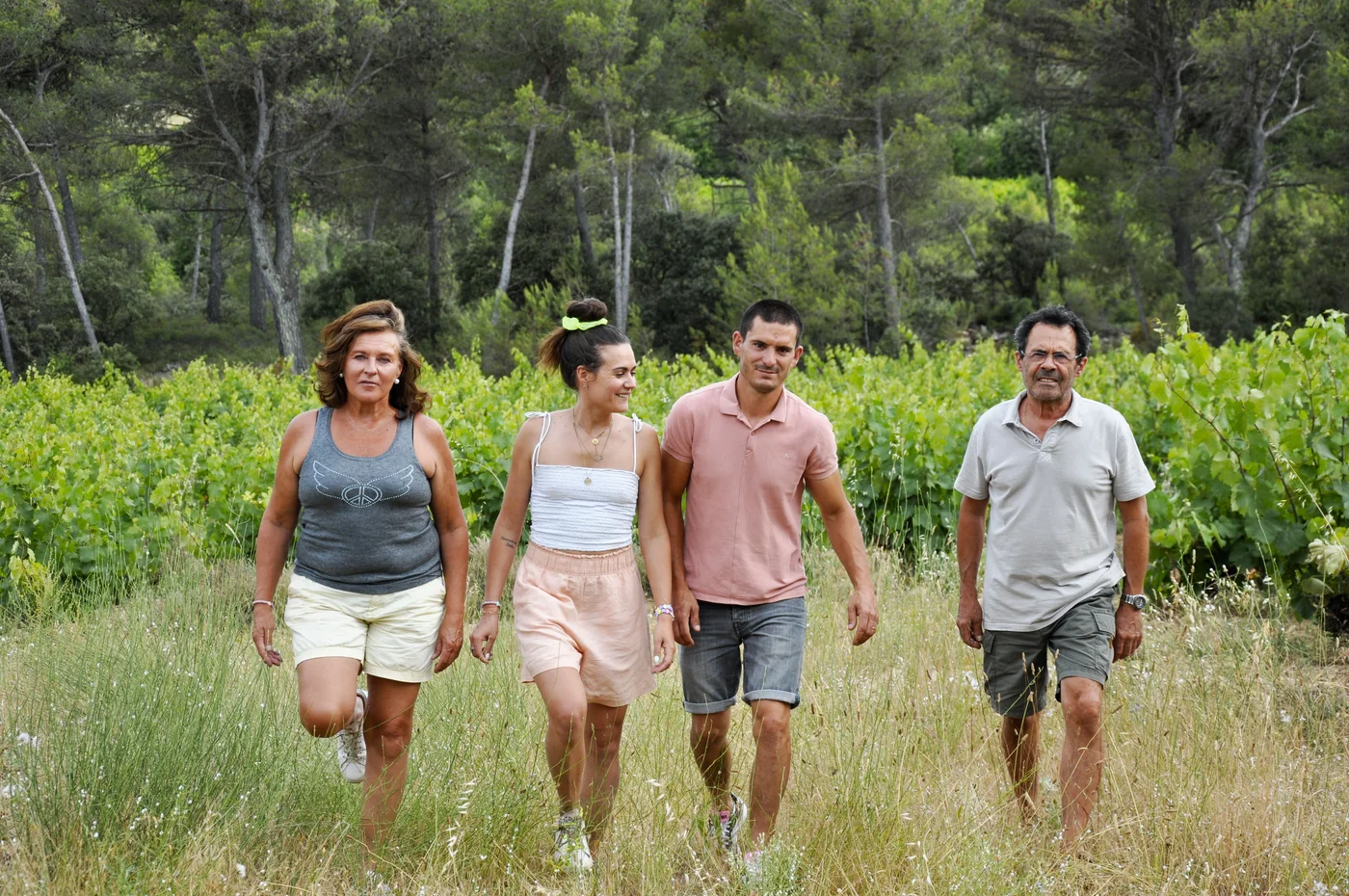Quatre membres de Villa Minna Vineyard marchent ensemble dans les vignes.