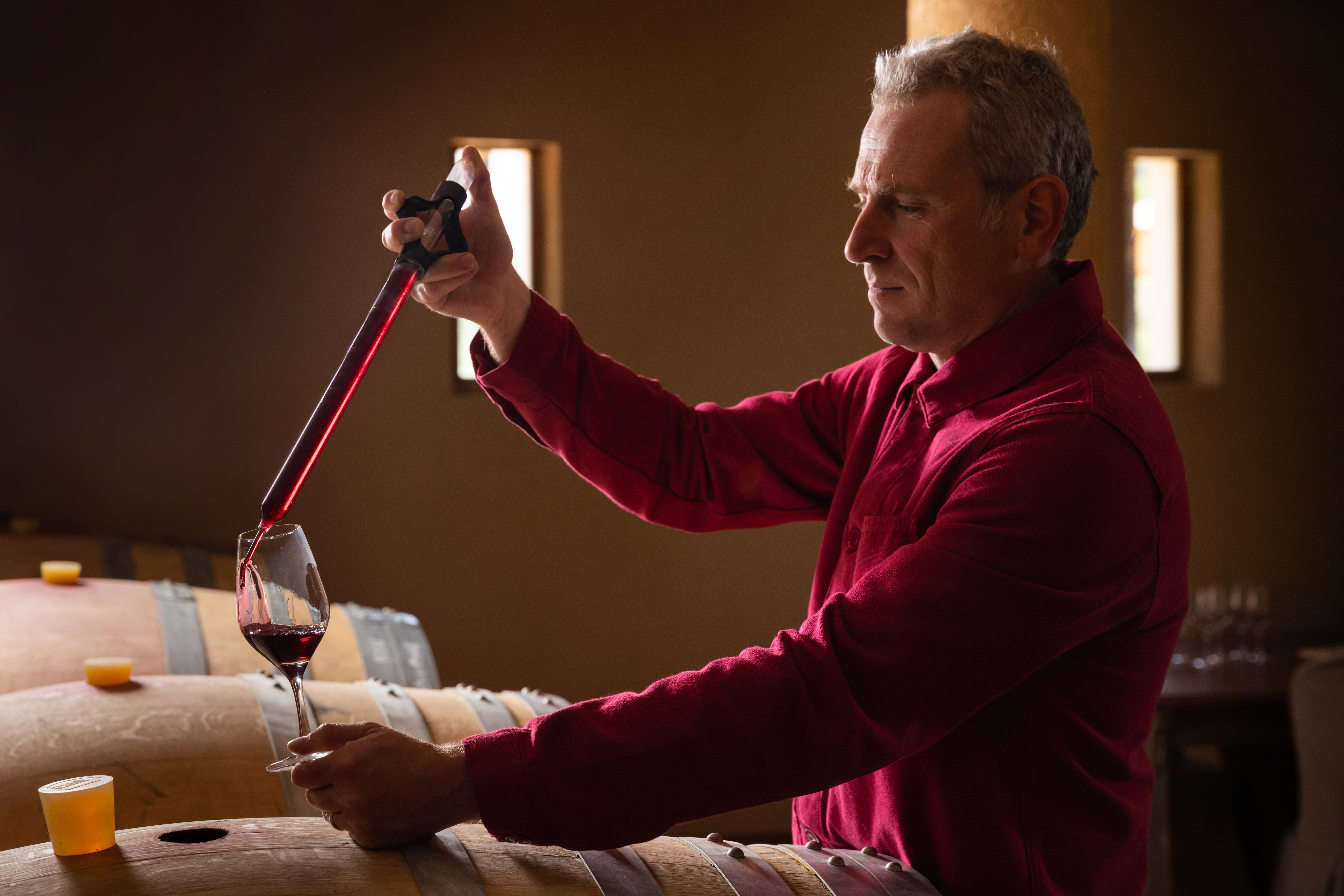 Au Mas de Cadenet, un vigneron prélève du vin à la pipette dans le chai.